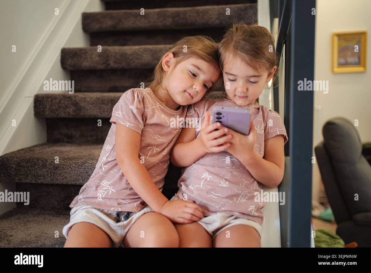 Due sorelle stanno guardando video su uno smartphone a casa Foto Stock