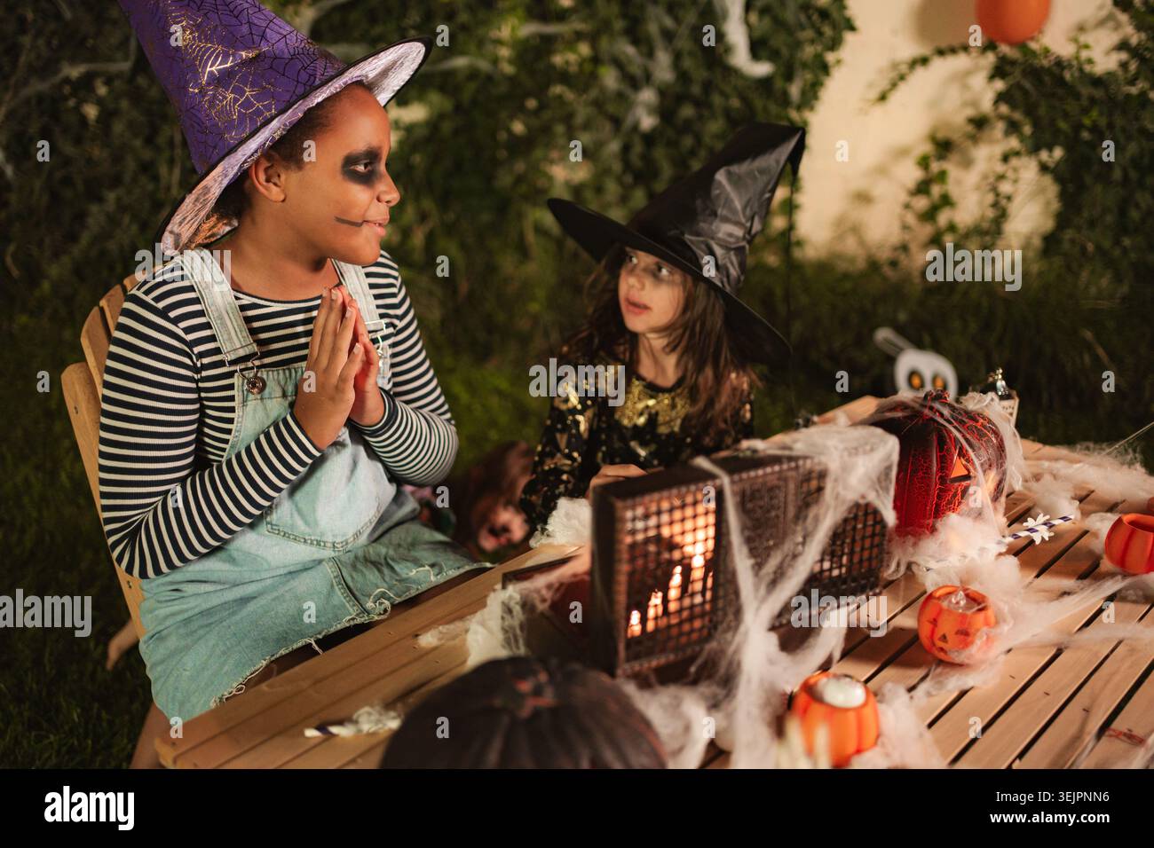Bambini che indossano costumi da strega che celebrano Halloween di notte Foto Stock