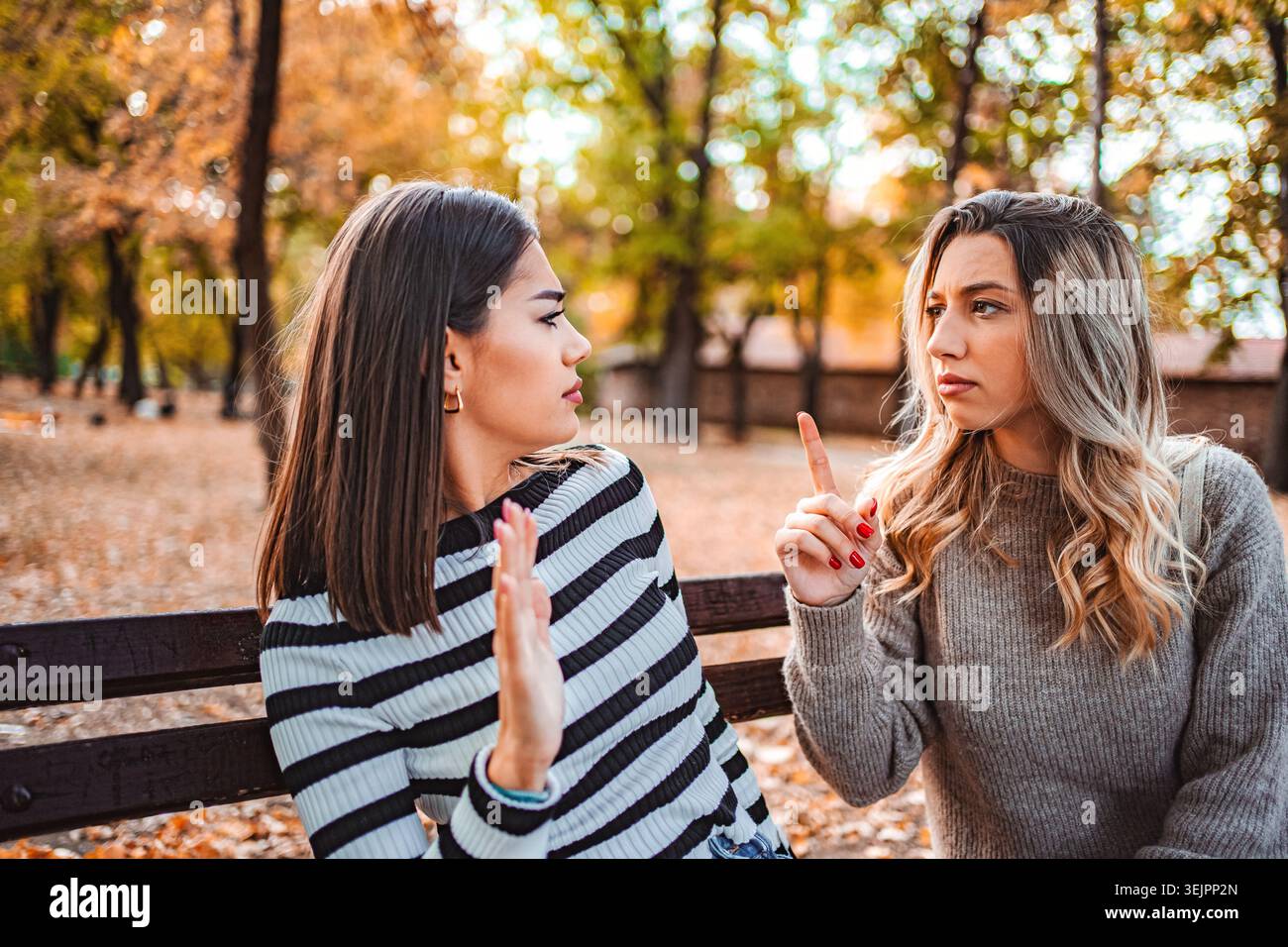 Due ragazze che condividono i pensieri su una splendida giornata autunnale nel parco Foto Stock