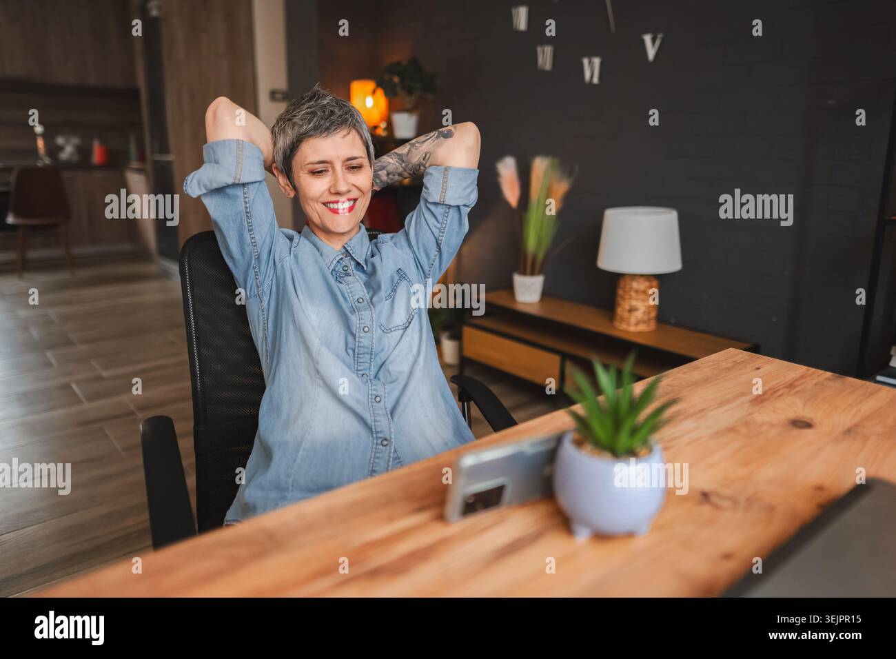 La freelance si rilassa e si gode una videochiamata nel suo ufficio domestico Foto Stock