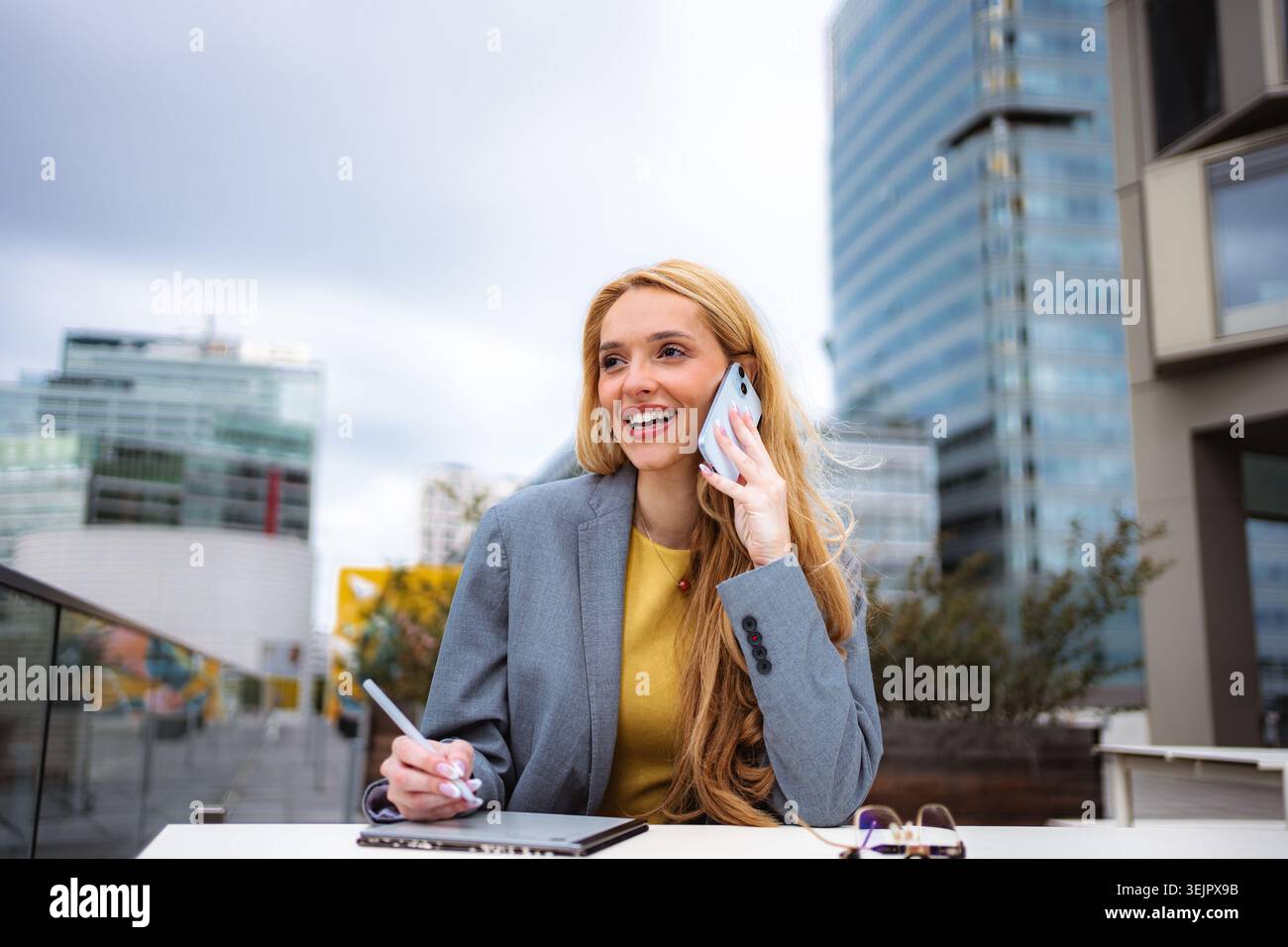 Donna d'affari che parla al telefono e lavora in remoto all'aperto Foto Stock