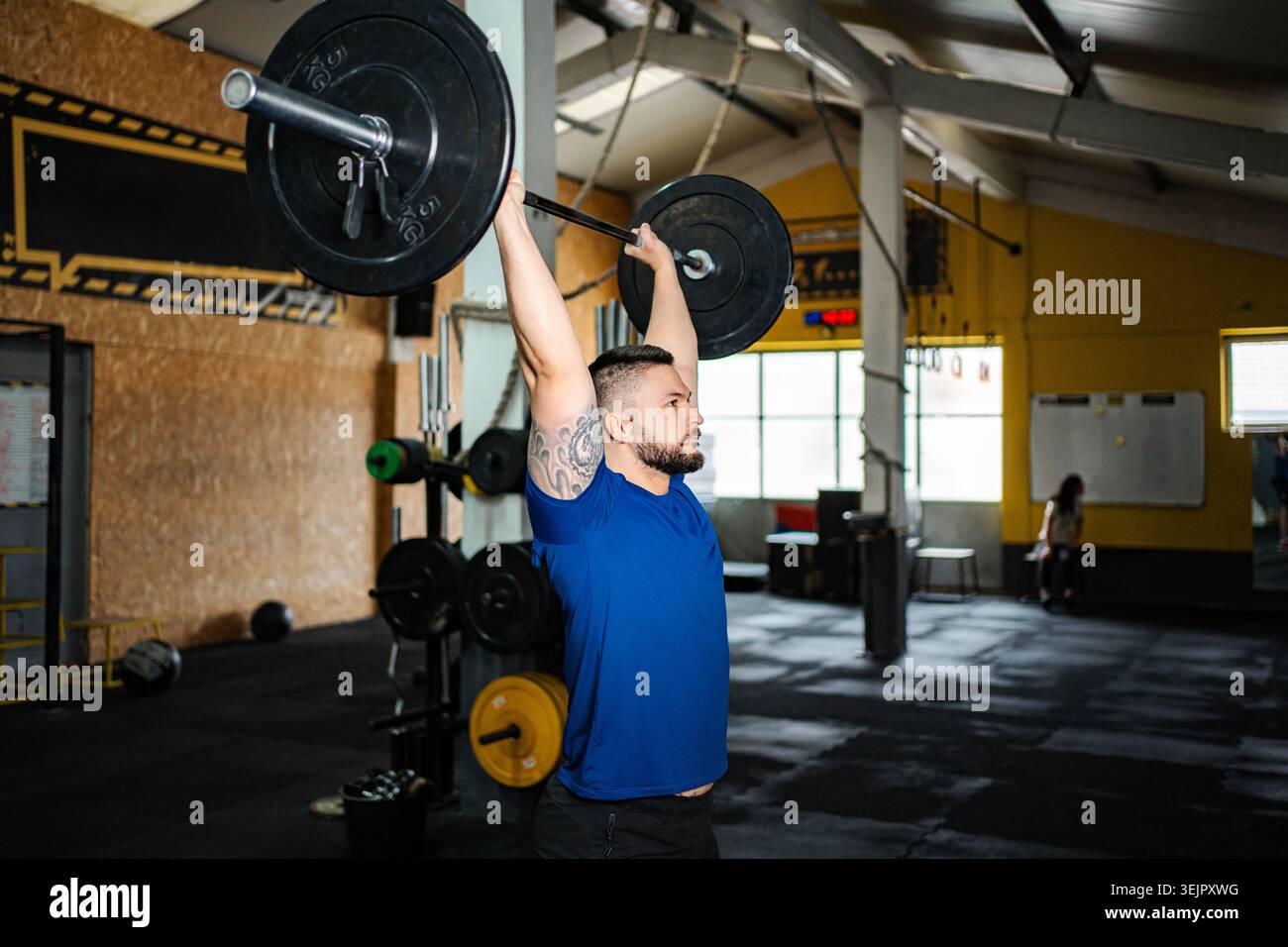 Atleta maschile che solleva un pesante barbell che spinge in alto in palestra Foto Stock