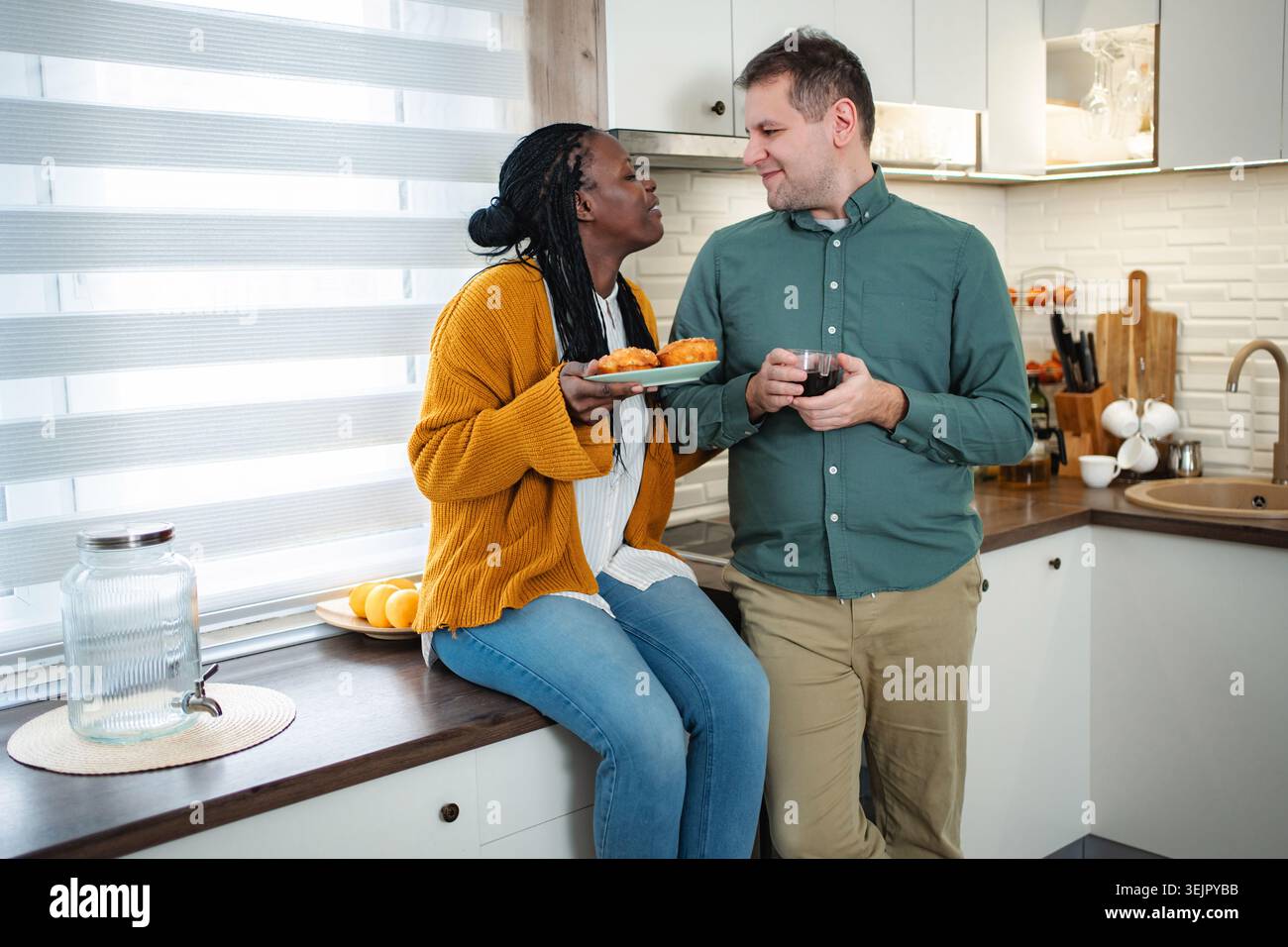 Coppie diverse che si godono la colazione insieme in una cucina moderna Foto Stock
