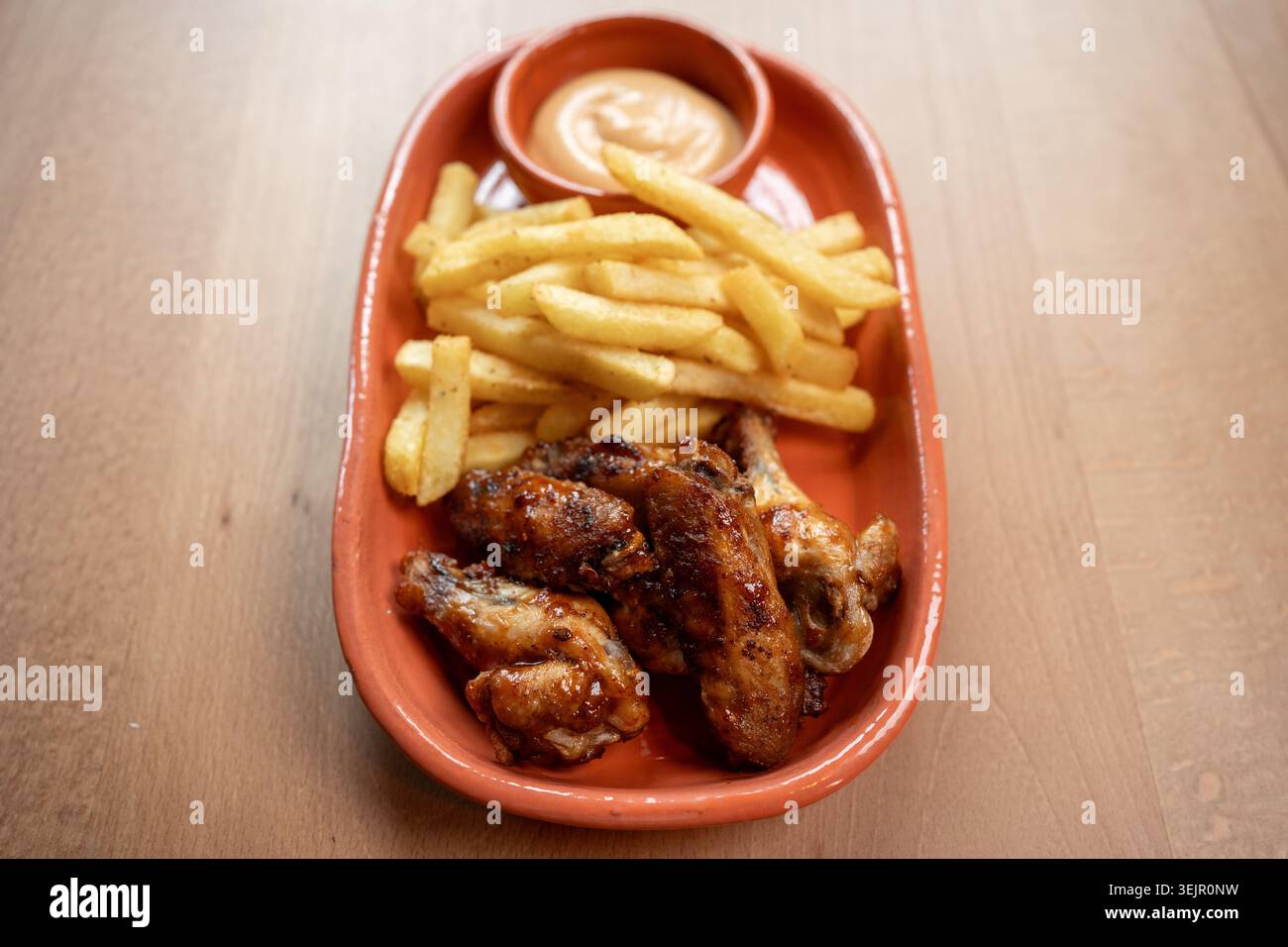 Ali di pollo croccanti e patatine fritte dorate con una gustosa salsa Foto Stock
