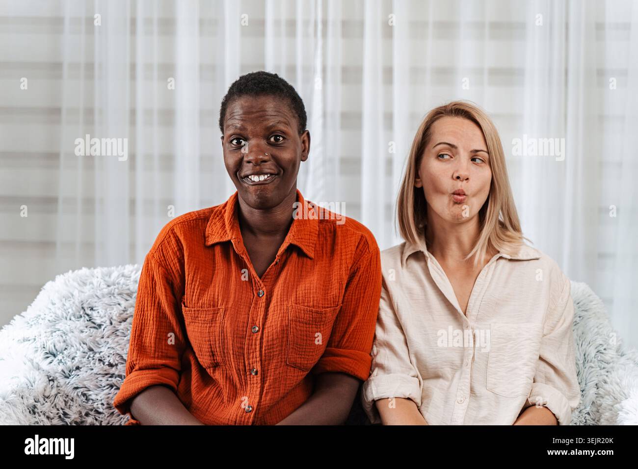 Due amiche che fanno facce divertenti e sorridono alla telecamera Foto Stock
