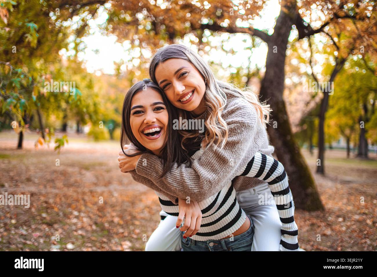 Momenti di gioia condivisi da due ragazze in un parco autunnale dorato Foto Stock