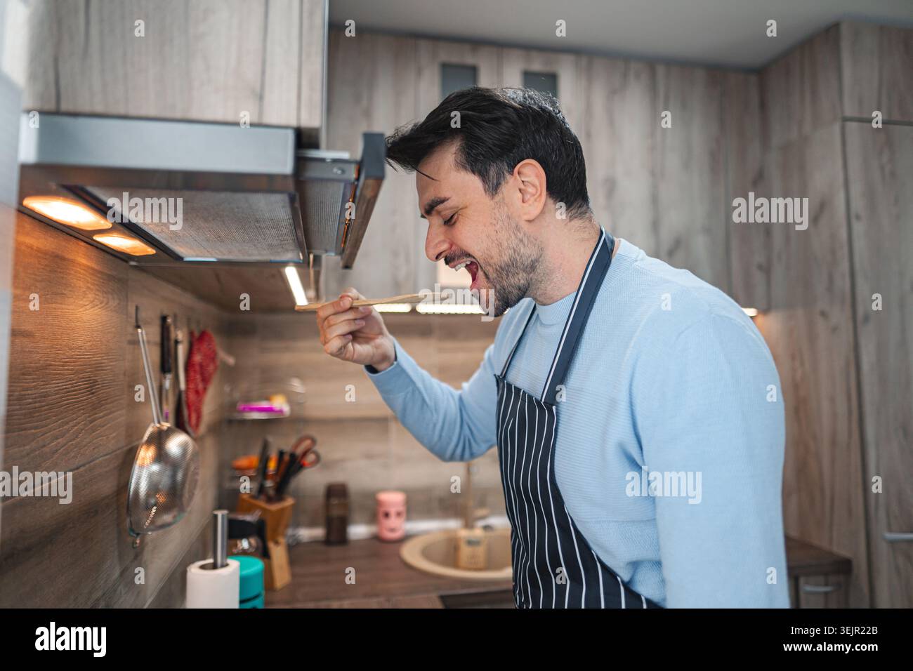 Uomo che tiene il cucchiaio in cucina Foto Stock