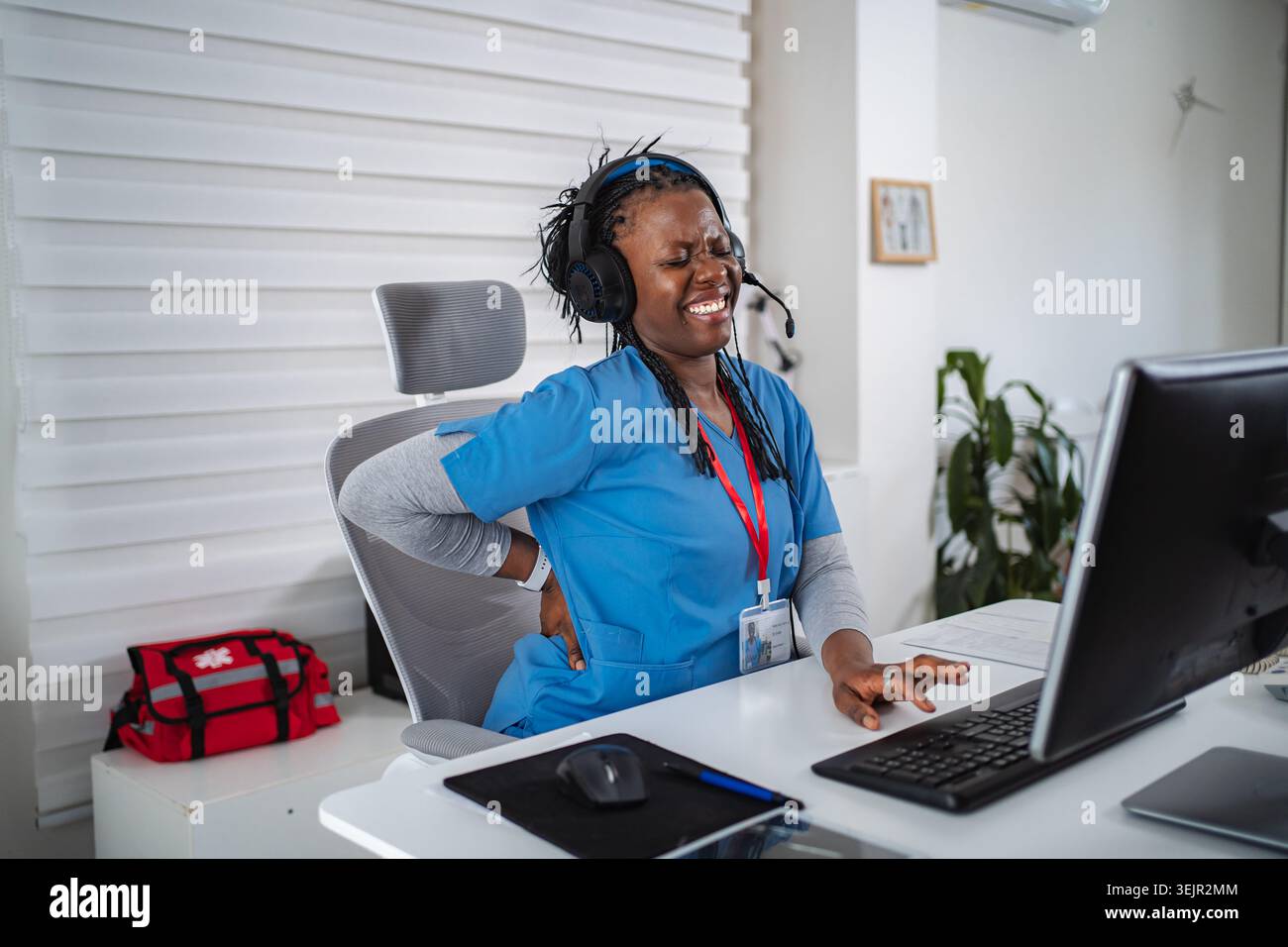 Lavoratrice sanitaria che soffre di mal di schiena mentre lavora in ufficio Foto Stock