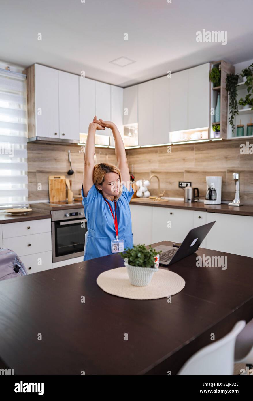 Dottoressa donna che si allunga nella sua cucina dopo l'incontro online Foto Stock