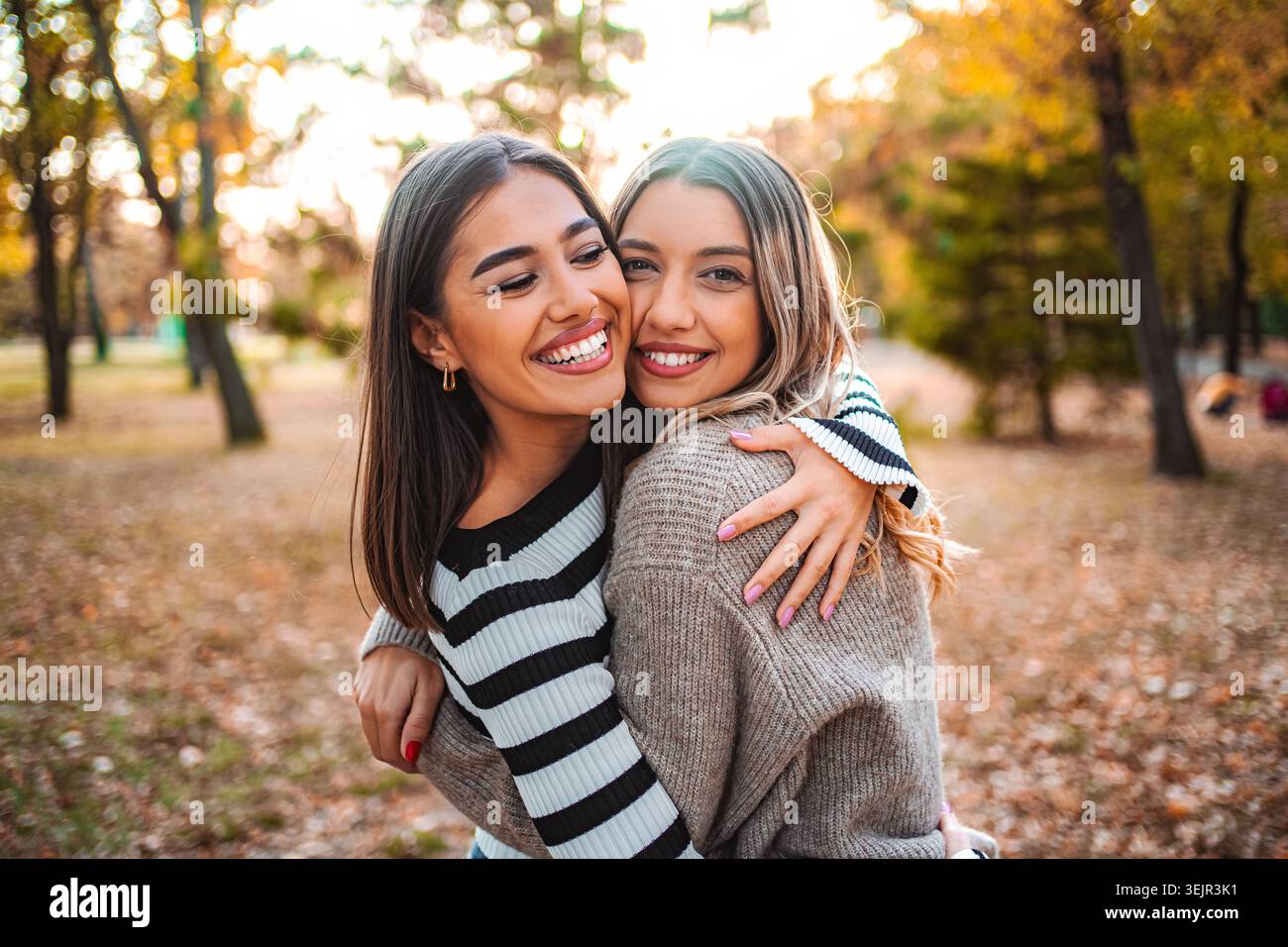 Celebra l'amicizia autunnale tra due ragazze in un parco colorato Foto Stock