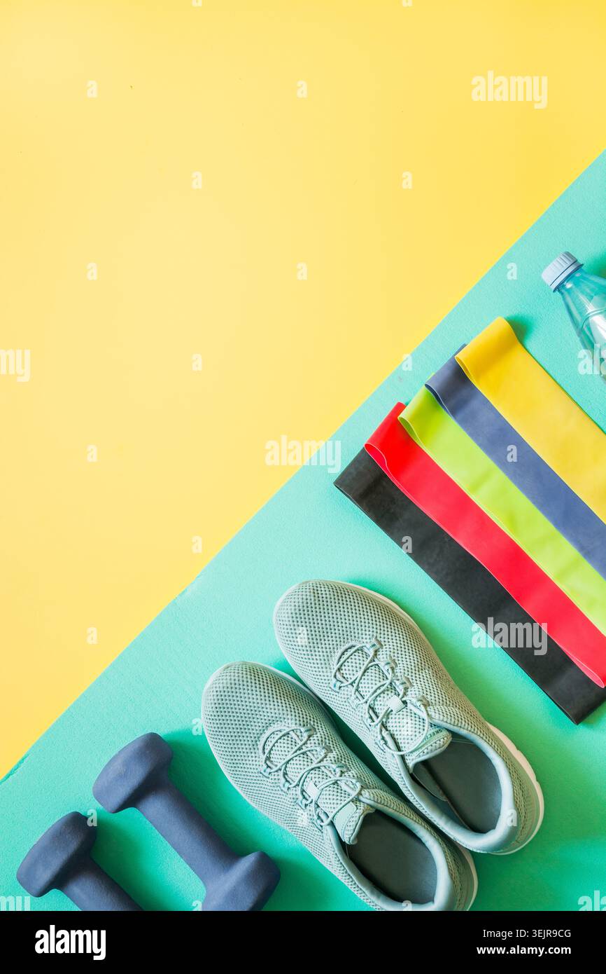 Attrezzature sportive, elastico, manubri, scarpe da fitness gialle. Foto Stock