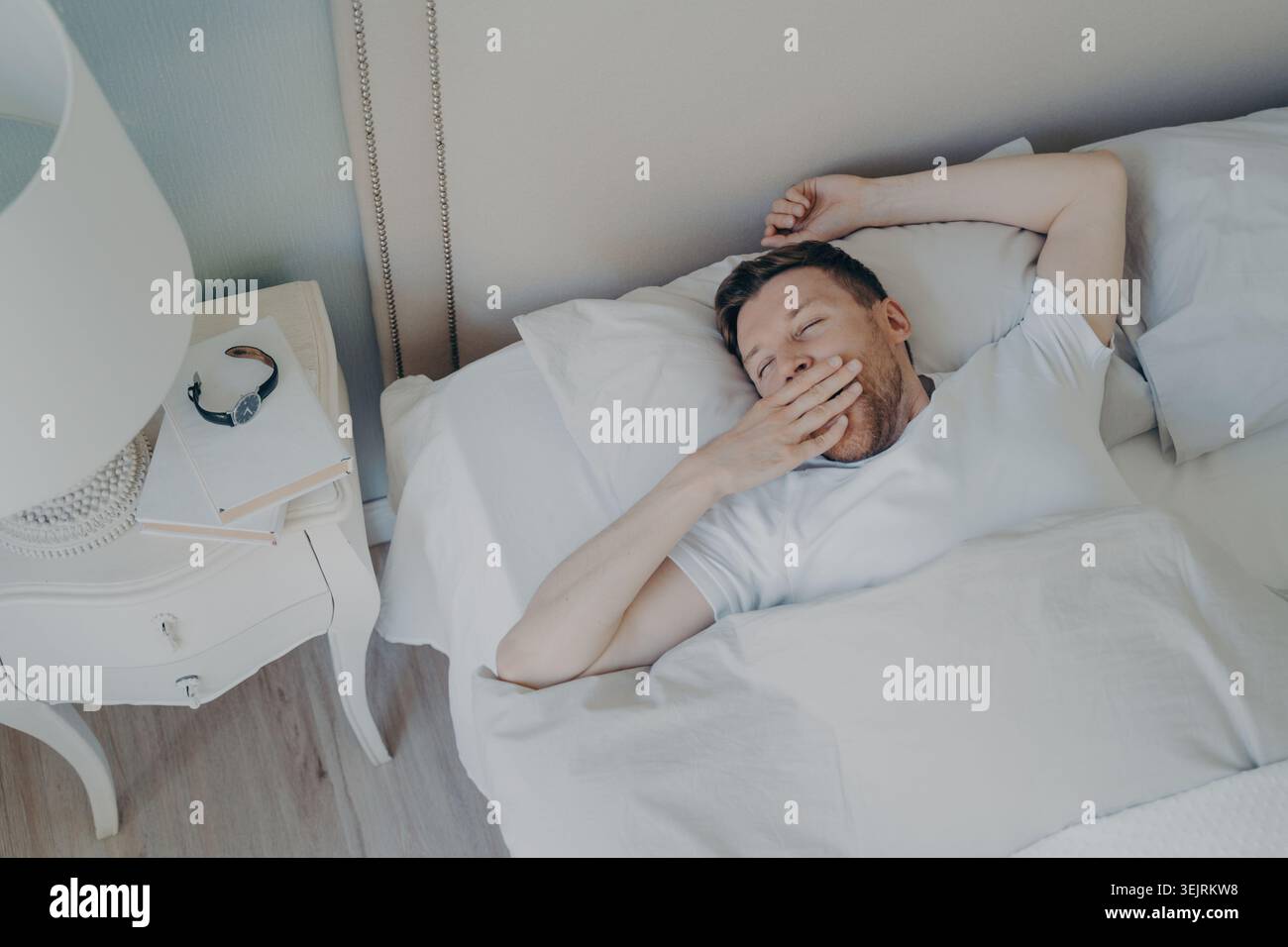 Allegro giovane attraente uomo che si sveglia al mattino a letto Foto Stock