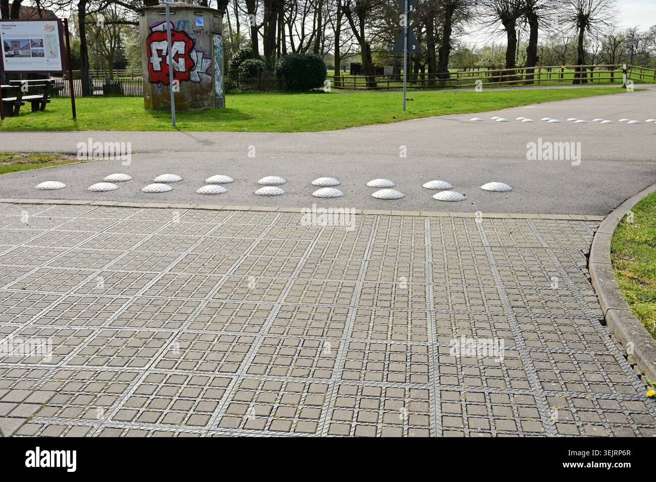 Xanten, Germania - aprile 3,2026: Dossi calmanti su strada vicino a graffiti e cartelli informativi Foto Stock