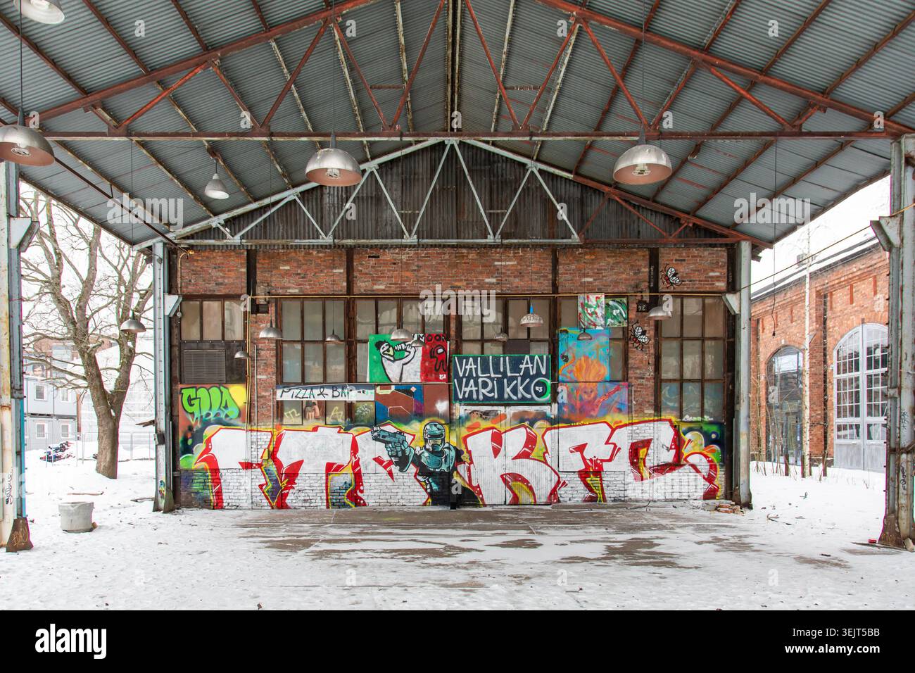 Vecchio edificio industriale in mattoni rossi ricoperto di graffiti nella zona di Konepaja nel distretto di Vallila, Helsinki, Finlandia Foto Stock