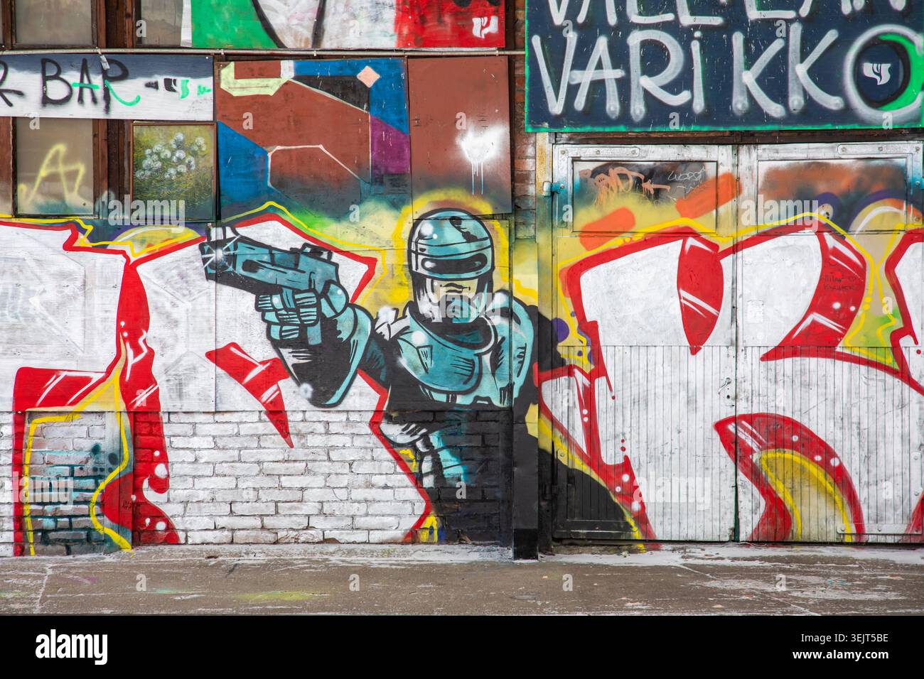 Street art: Graffiti Robocop sul vecchio edificio industriale di Konepaja nel quartiere Vallila di Helsinki, Finlandia. Foto Stock