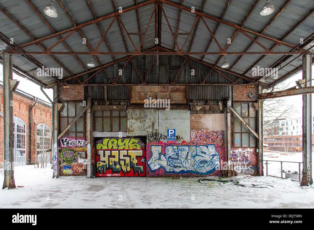 Vecchio magazzino industriale coperto di graffiti nel quartiere Konepaja di Vallila a Helsinki, Finlandia Foto Stock