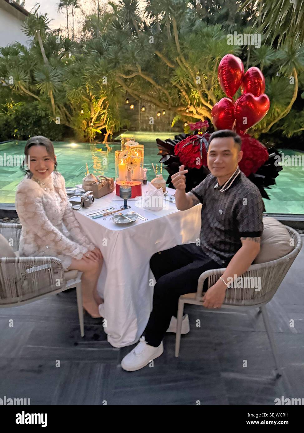 Una coppia dalla Corea del Sud festeggia con stile con un enorme mazzo di rose e prima di cena accanto alla piscina dell'hotel il giorno di San Valentino in un hotel di lusso - Immagine stock catturata con smartphone