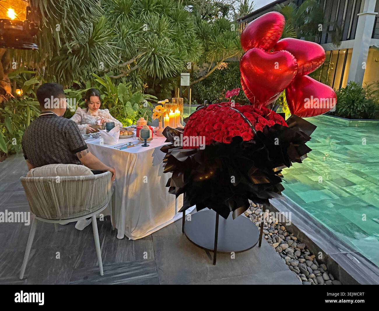 Una coppia dalla Corea del Sud festeggia con stile con un enorme mazzo di rose e prima di cena accanto alla piscina dell'hotel il giorno di San Valentino in un hotel di lusso - Immagine stock catturata con smartphone