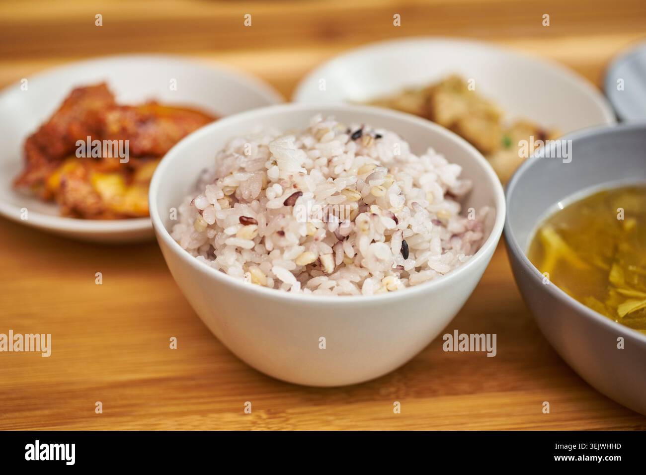 Una calda ciotola di sano riso coreano multi-grano viene catturata su un tavolo di legno. Con contorni sfocati, rappresenta perfettamente un autentico mea quotidiano Foto Stock