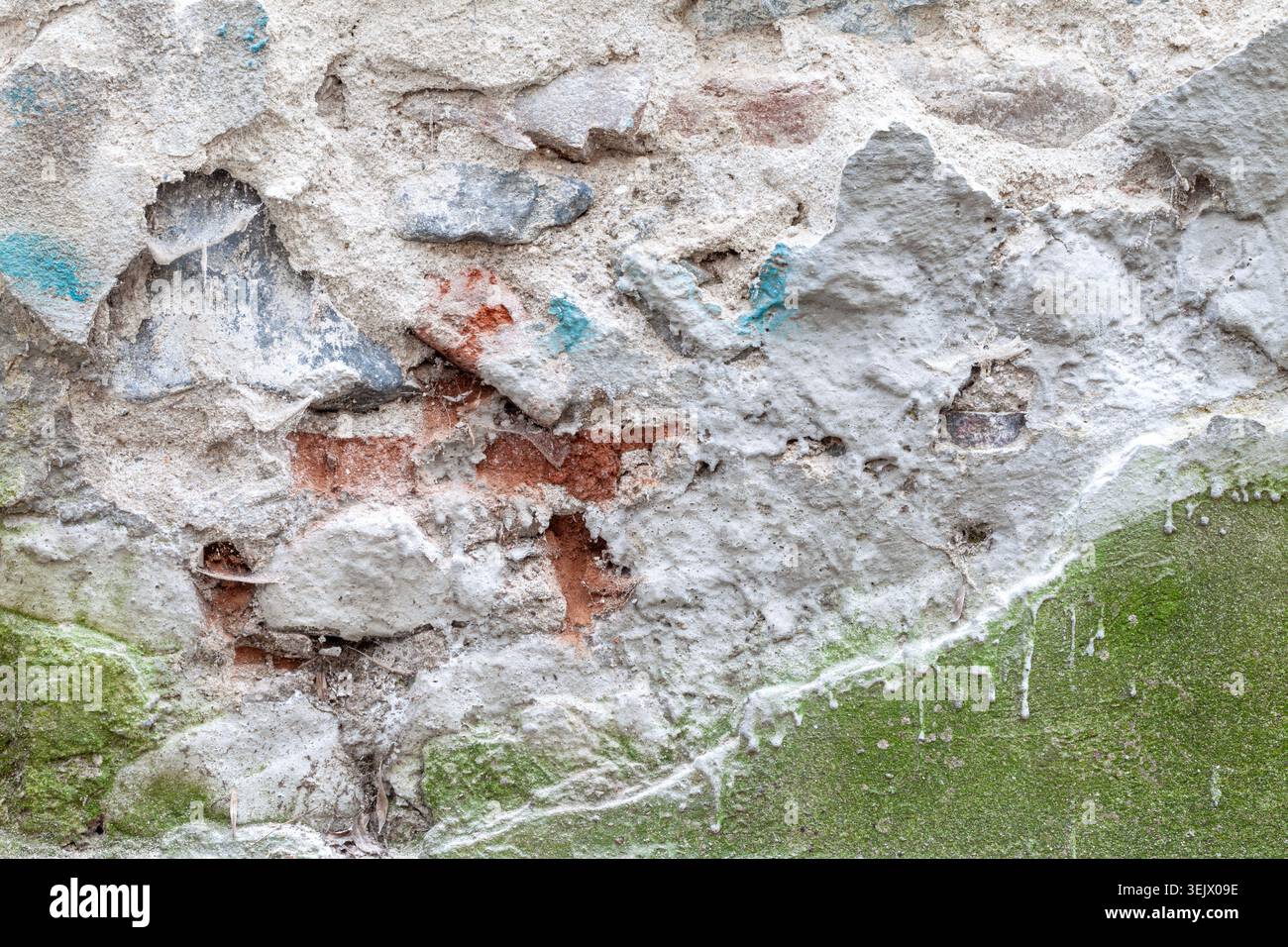 Materiali di intonaco diversi che coprono una vecchia struttura di fondo in mattoni e pietra Foto Stock