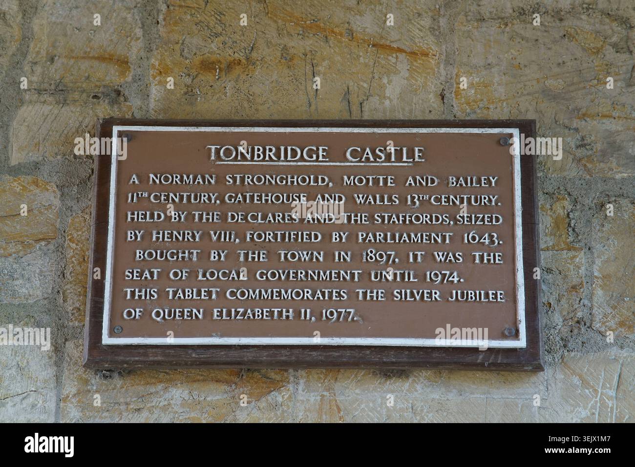 Targa informativa storica del castello di Tonbridge montata su un'antica parete di pietra, che illustra la storia e il patrimonio normanno del castello. Foto Stock