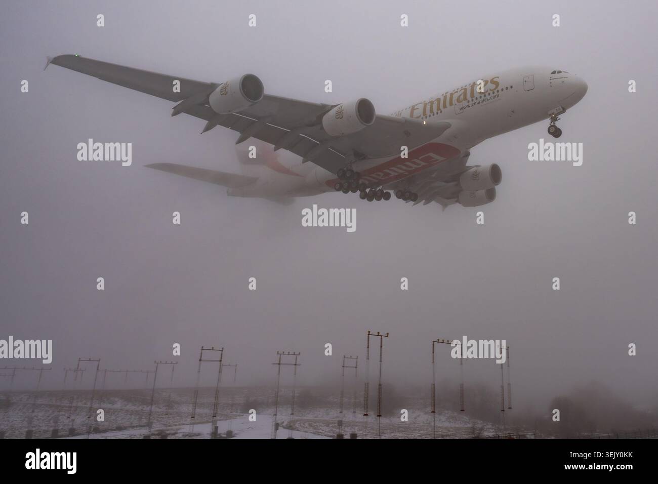 MISSISSAUGA, CANADA - 24 GENNAIO 2024: Un enorme aereo passeggeri a due piani Emirates Airbus A380 superjumbo emerge dalla fitta nebbia e dalle nuvole. Foto Stock