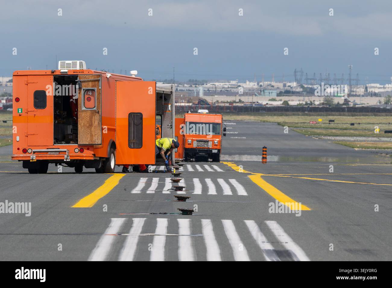 MISSISSAUGA, CANADA – 17 AGOSTO 2025: Un equipaggio di manutenzione elettrica dell'aeroporto effettua una manutenzione pesante sulle luci della linea centrale della pista. Foto Stock