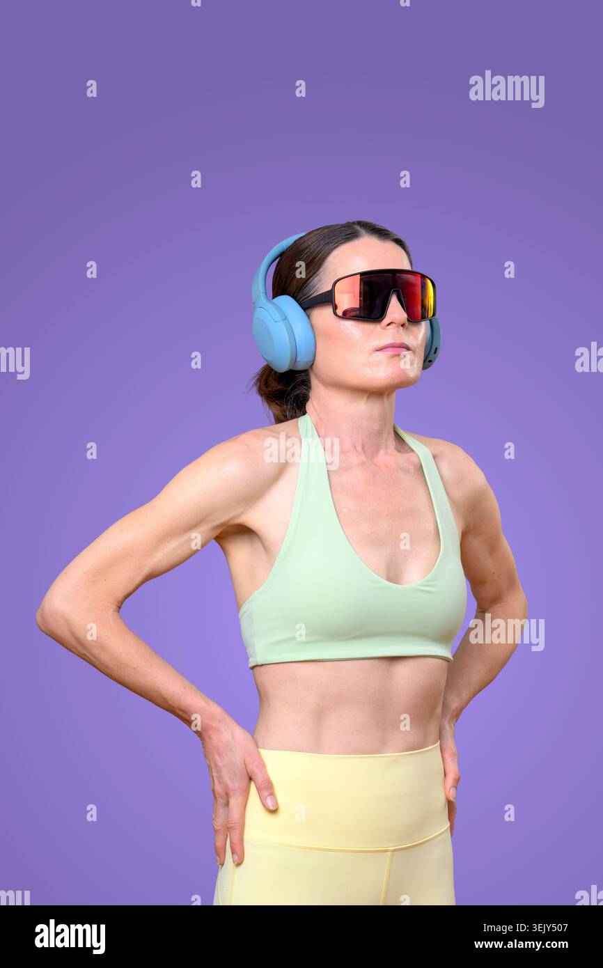 donna sportiva che indossa le cuffie, sfondo viola Foto Stock