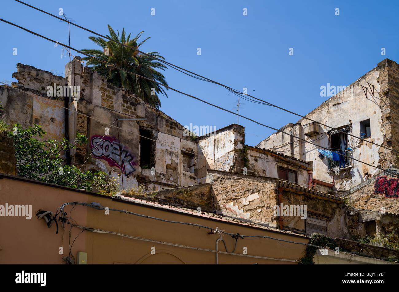 In Sicilia, gli edifici in rovina mostrano segni di abbandono. I graffiti segnano le pareti sbriciolate, ma il bucato è appeso all'esterno, mostrando che la vita si perde Foto Stock