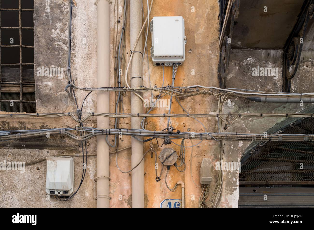 Una caotica rete di cavi e scatole elettriche copre la facciata dell'edificio numero 16, riflettendo anni di lavoro infrastrutturale ad hoc necessario Foto Stock