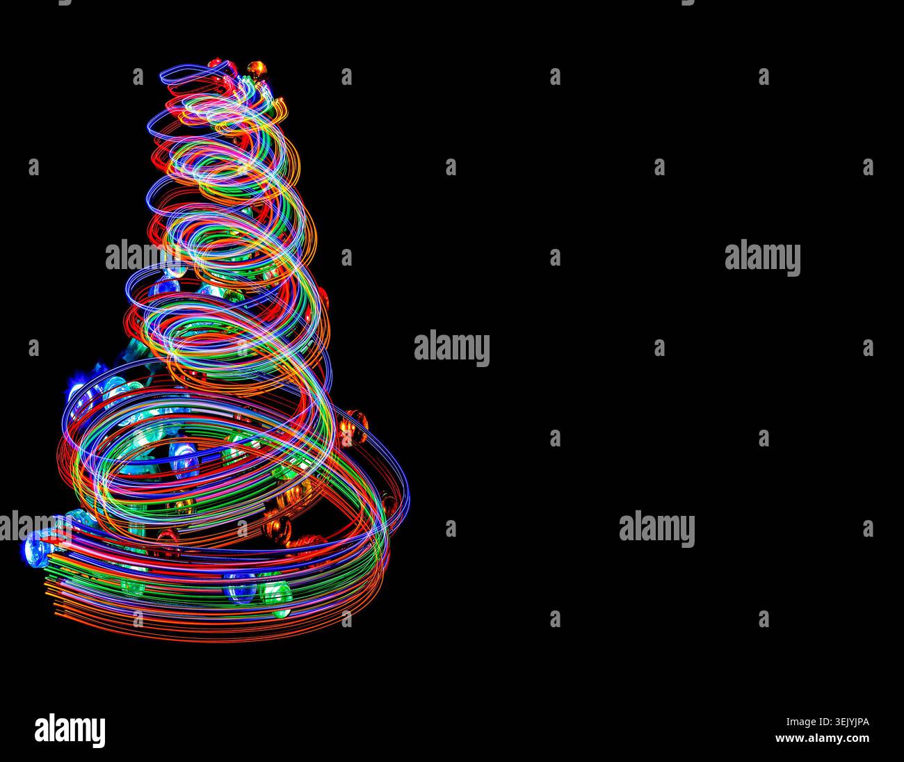 I sentieri di luce delle festività si alternano a formare un albero di Natale, catturando la magia, il colore e il movimento delle festività natalizie con uno spazio per copie nere. Foto Stock
