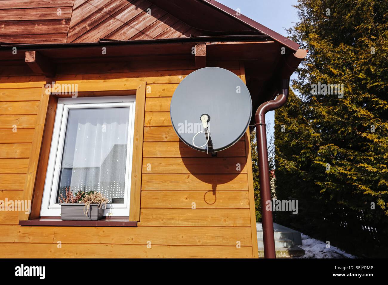Parabola satellitare montata sull'esterno della casa in legno. Ricezione televisiva domestica background che illustra la tecnologia di comunicazione residenziale. Foto Stock