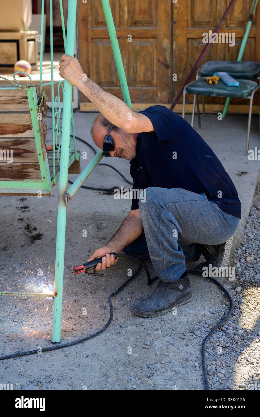 Bukhara, Uzbekistan - 12 aprile 2026: Uomo che salda un vecchio portico che alza. Foto Stock