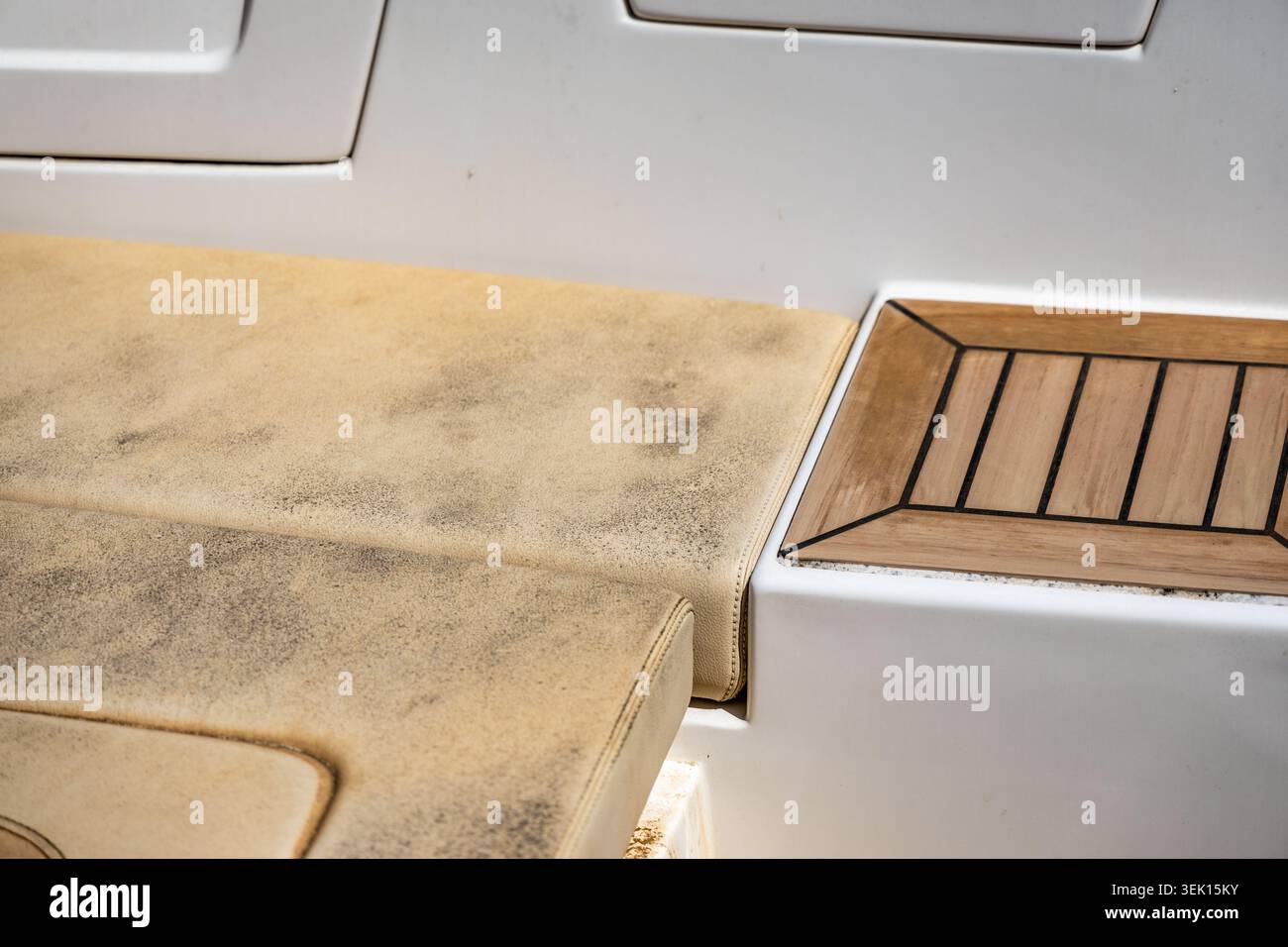 Una vista dettagliata della selleria beige invecchiata e testurizzata accanto a una sezione del ponte in legno lucido su un vaso, evidenziando il contrasto nei materiali e nell'usura Foto Stock