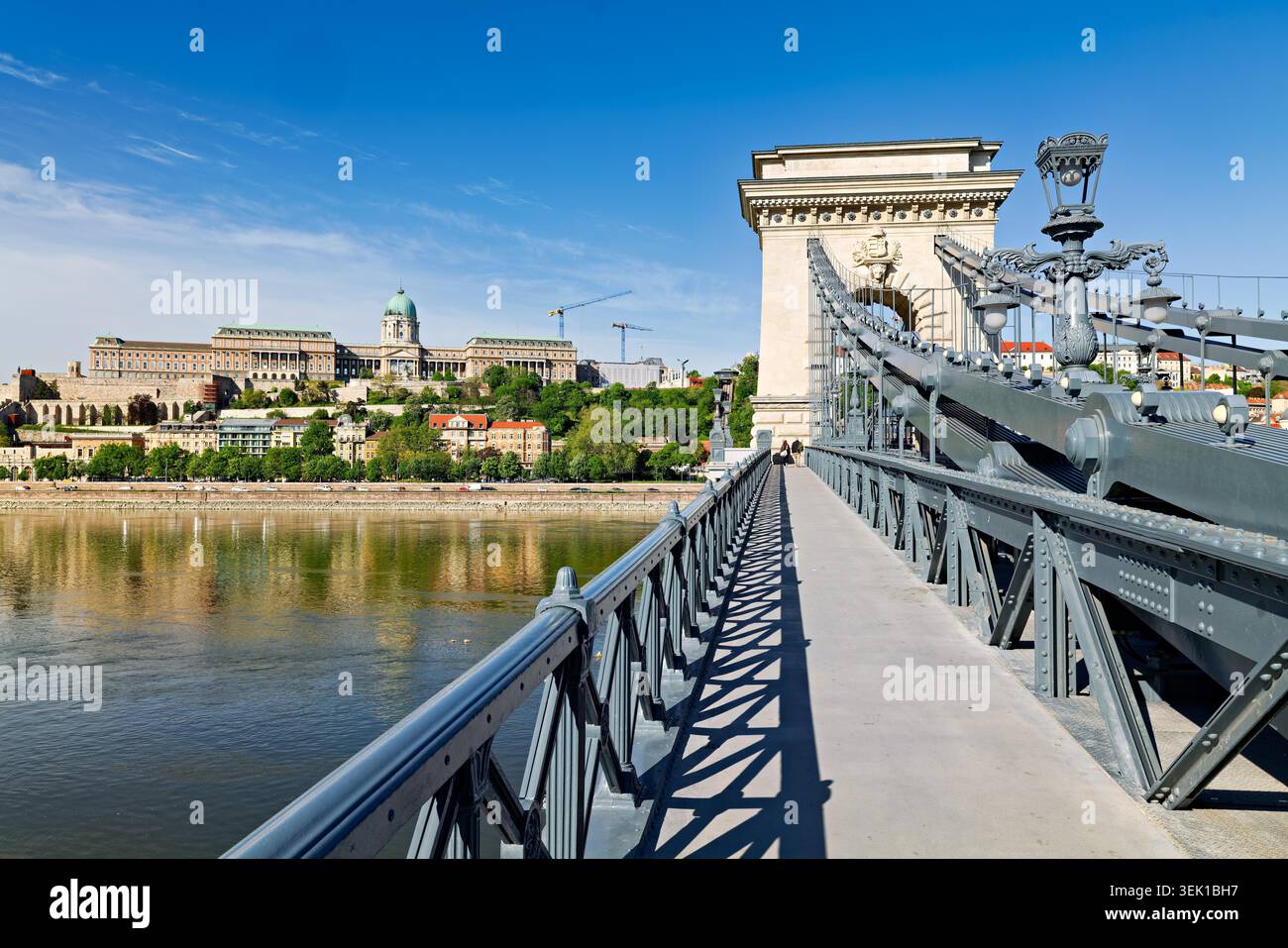 La gente attraversa il Ponte delle catene di Széchenyi mentre il Castello di Buda si erge alto sullo sfondo sotto il cielo limpido di Budapest, Ungheria. Foto Stock