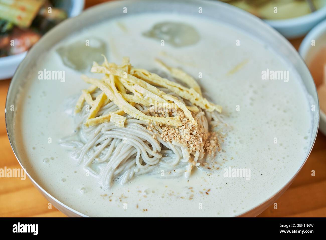 Coreano Memil Kongguksu, spaghetti freddi di grano saraceno in cremoso brodo di soia. Condito con guarnigione di uova e servito con contorni per un sano pasto estivo. Foto Stock