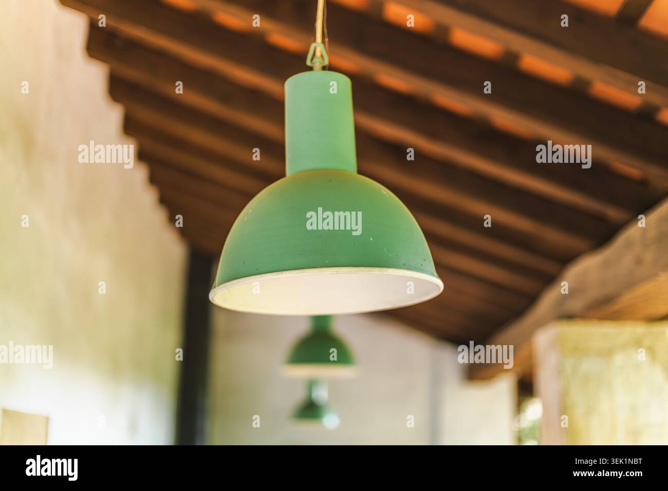 Lampada a sospensione industriale vintage verde appesa sotto il soffitto in legno rustico Foto Stock