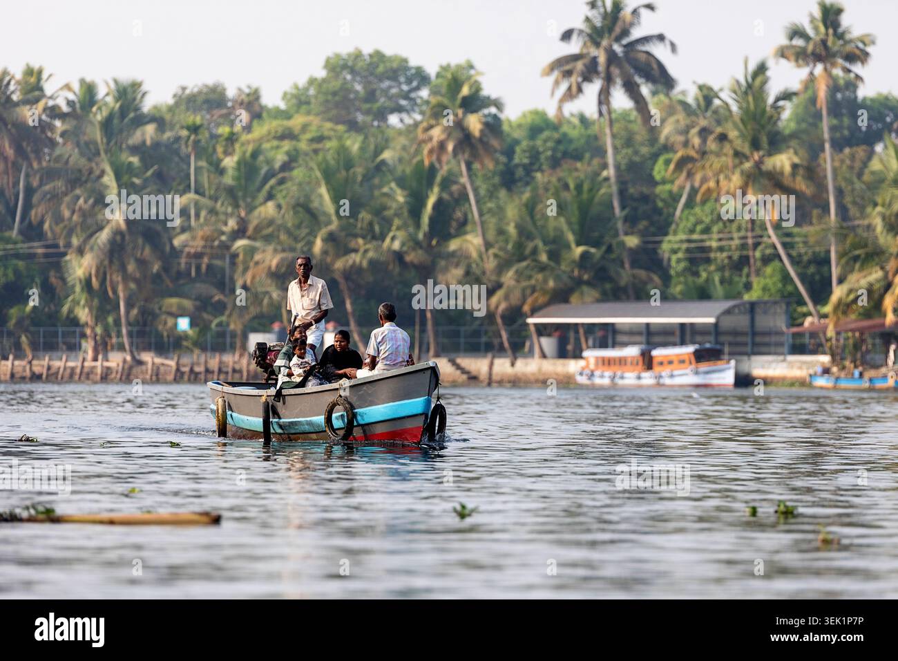 Uomini del posto a bordo di una tradizionale barca di legno nelle acque secondarie vicino ad Alleppey nel Kerala, barcaiolo come tassista che trasporta merci e persone locali Foto Stock