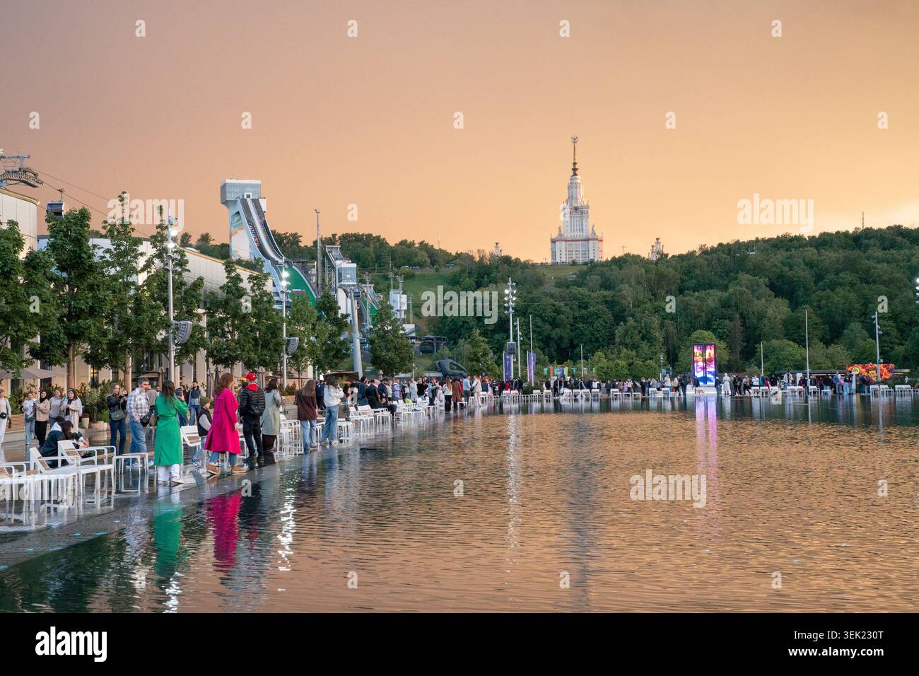 Mosca, Russia - 30 maggio 2026: I visitatori camminano lungo la passeggiata illuminata della fontana a Luzhniki, l'edificio dell'Università statale di Mosca, le colline dei passeri, il tramonto Foto Stock