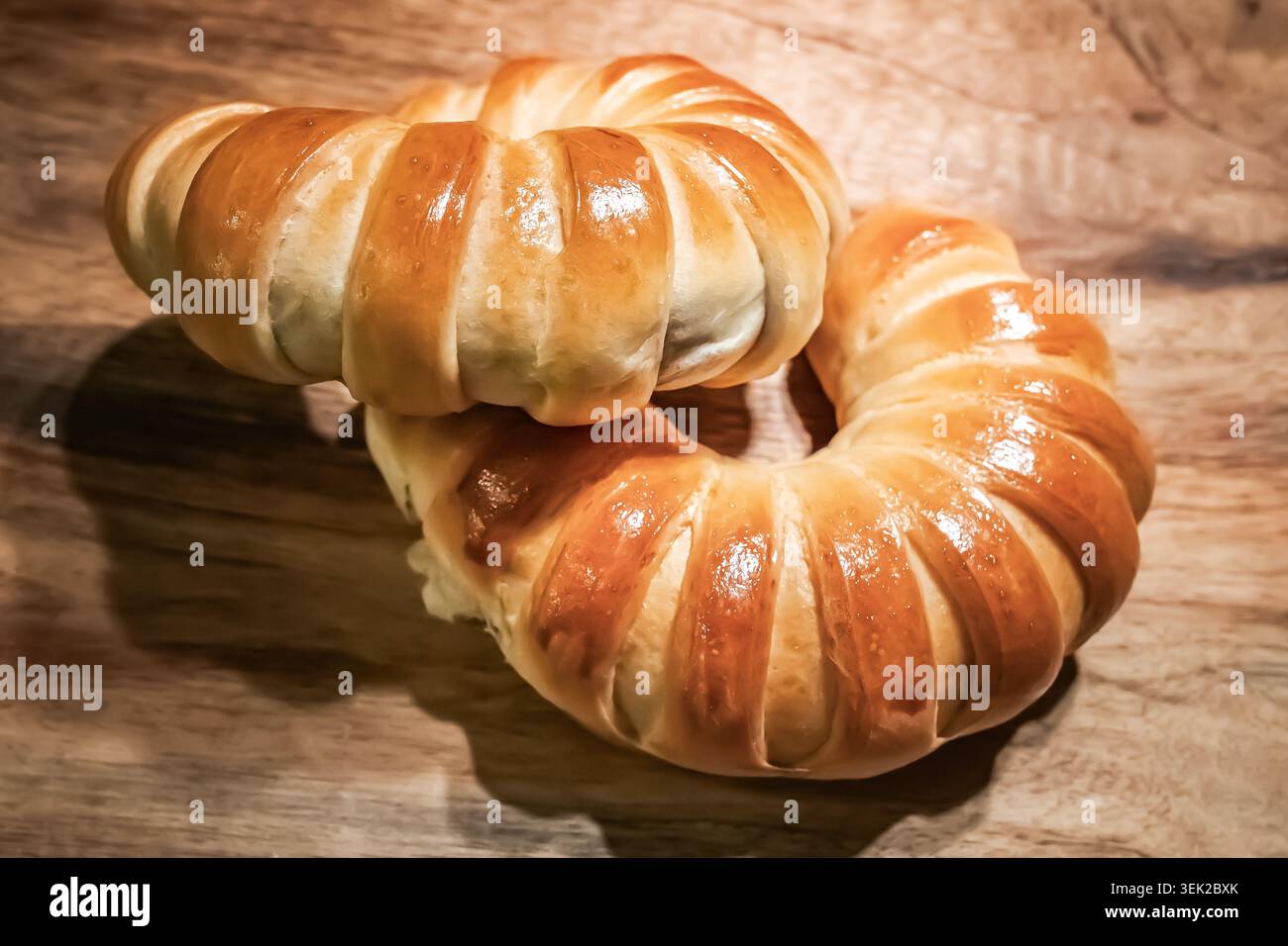 Rotoli di pane freschi Golden Crescent su un tavolo in legno rustico. Panini dorati appena sfornati con crosta lucida. Foto Stock