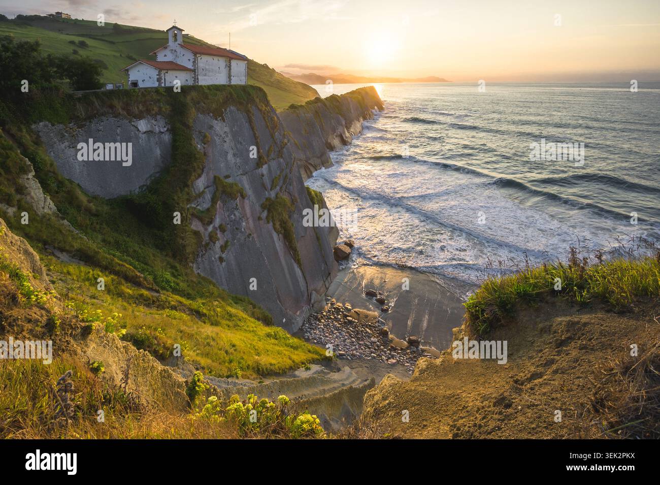 Antica Cappella sulle suggestive scogliere Flysch al tramonto dorato sull'Oceano Atlantico, Zumaia, Paesi Baschi, Spagna Foto Stock