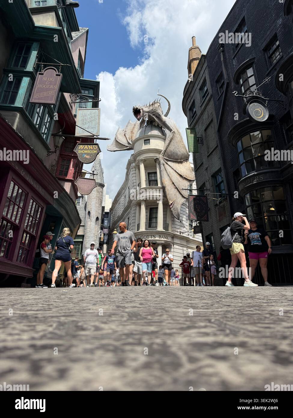 ORLANDO, FL - 31 maggio 2026: I turisti affollano la strada acciottolata di Diagon Alley sotto il gigante drago Gringotts agli Universal Studios. Foto Stock