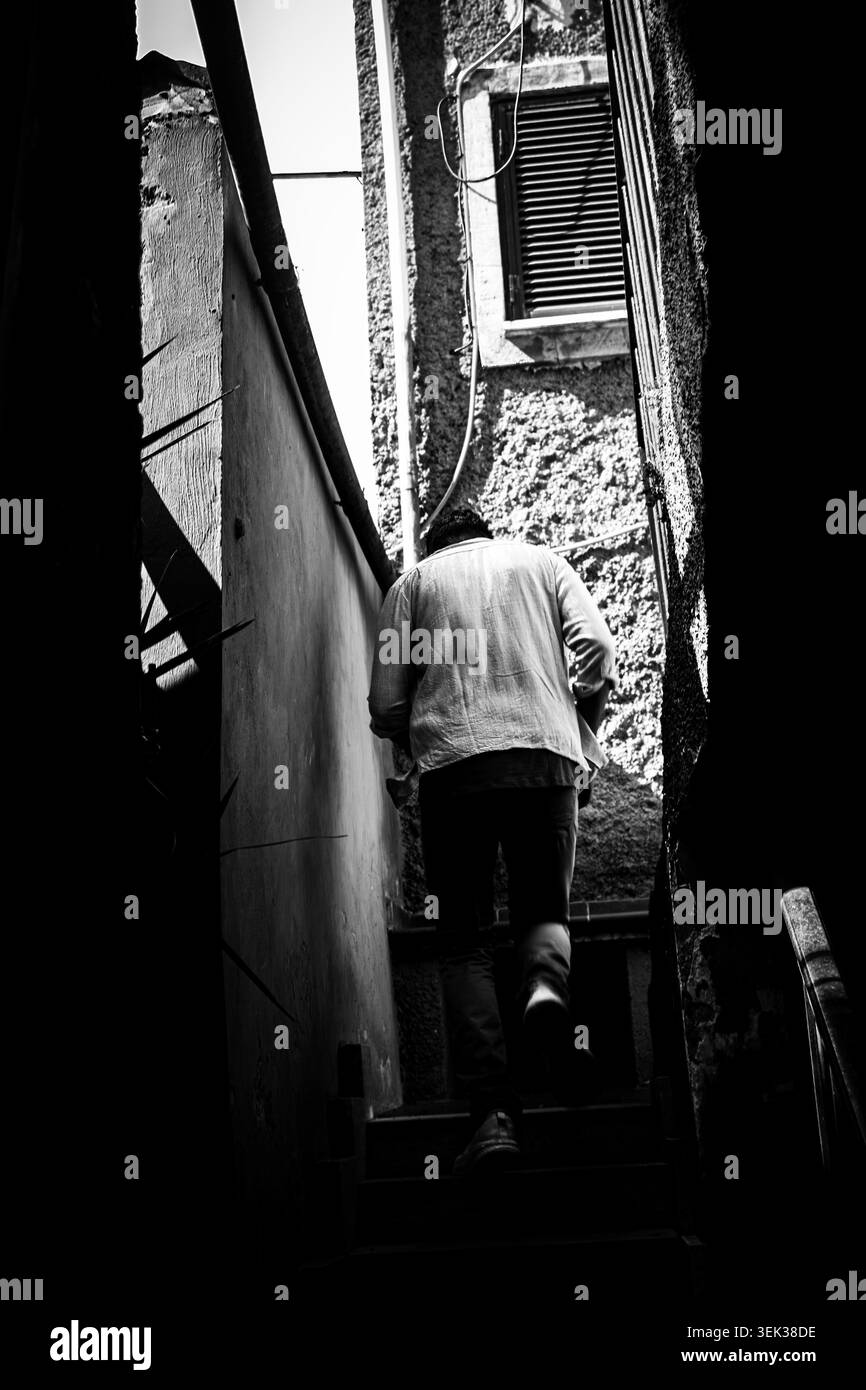 Persona indefinita che sale le scale della sua casa. Fotografia di strada Foto Stock