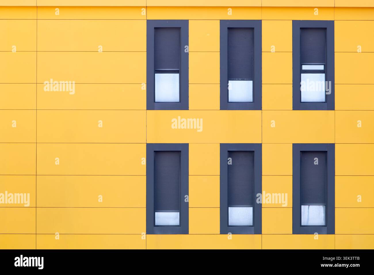 Edificio moderno di colore giallo con finestre ripetitive e motivi geometrici Foto Stock
