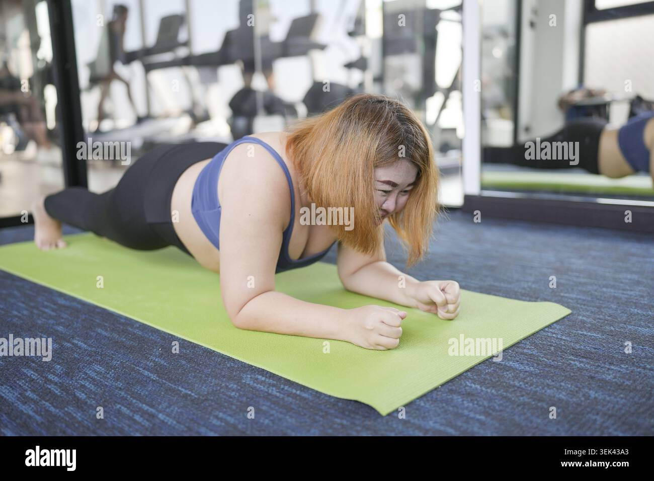 Donna in sovrappeso esercizi per la perdita di peso. Esercizi di plank in posizioni strette sul tappetino Yoga in palestra felice concetto per donna grassa, dieta, guarire Foto Stock