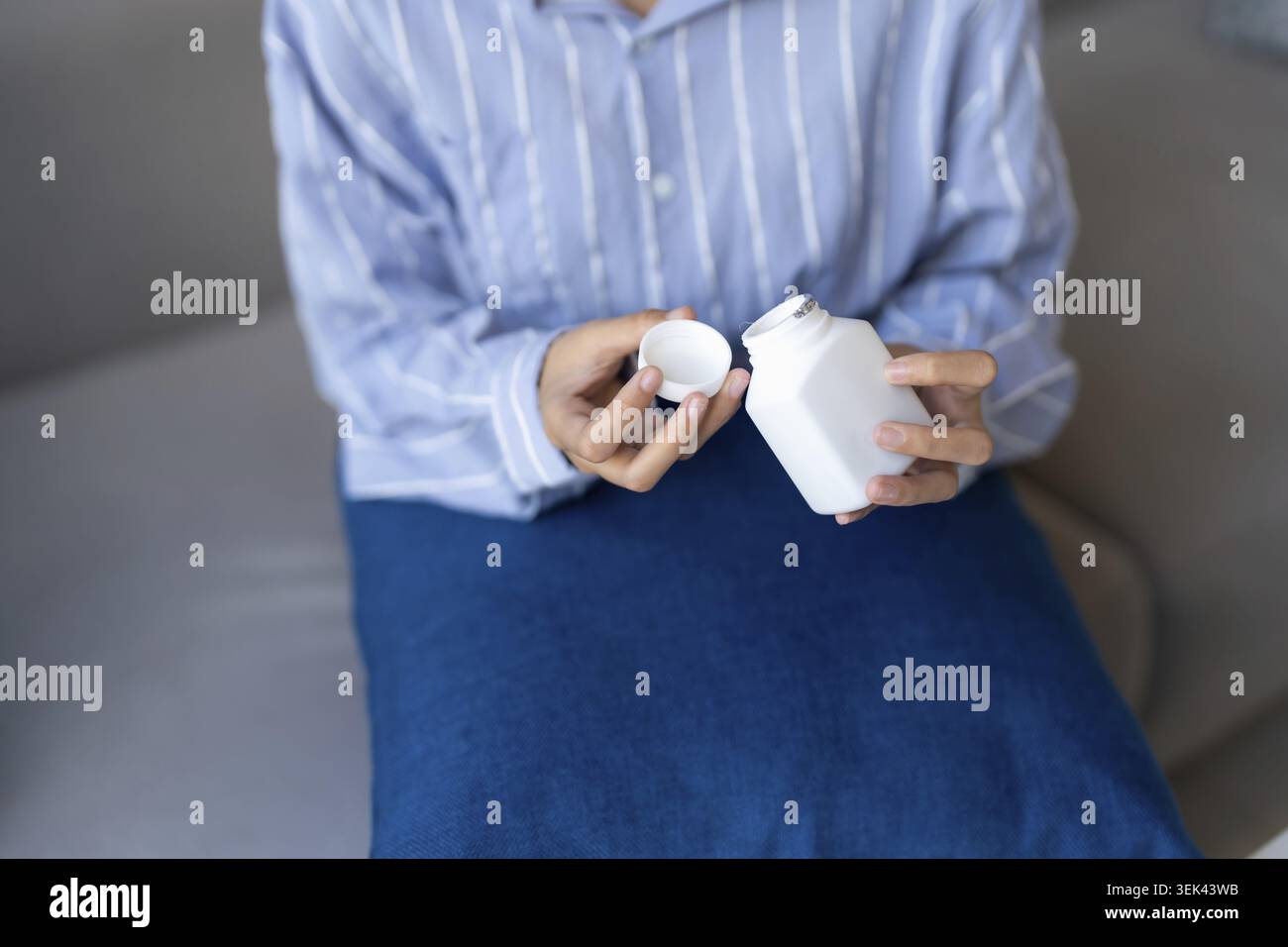 Donna asiatica in procinto di prendere vitamine dalla bottiglia, cura di sé e benessere a casa Foto Stock