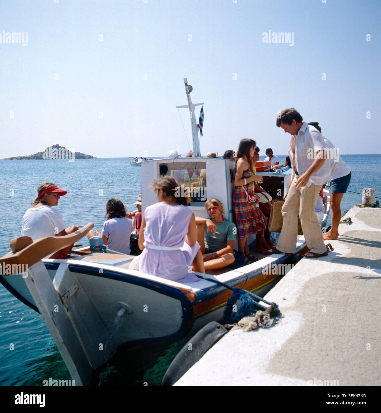 Personen steigen auf Samos auf ein kleines Urlaubsschiff oder verlassen es. Im Hintergrund ist das Meer mit einer kleinen Insel zu sehen. Griechenland, um 1985. Foto Stock