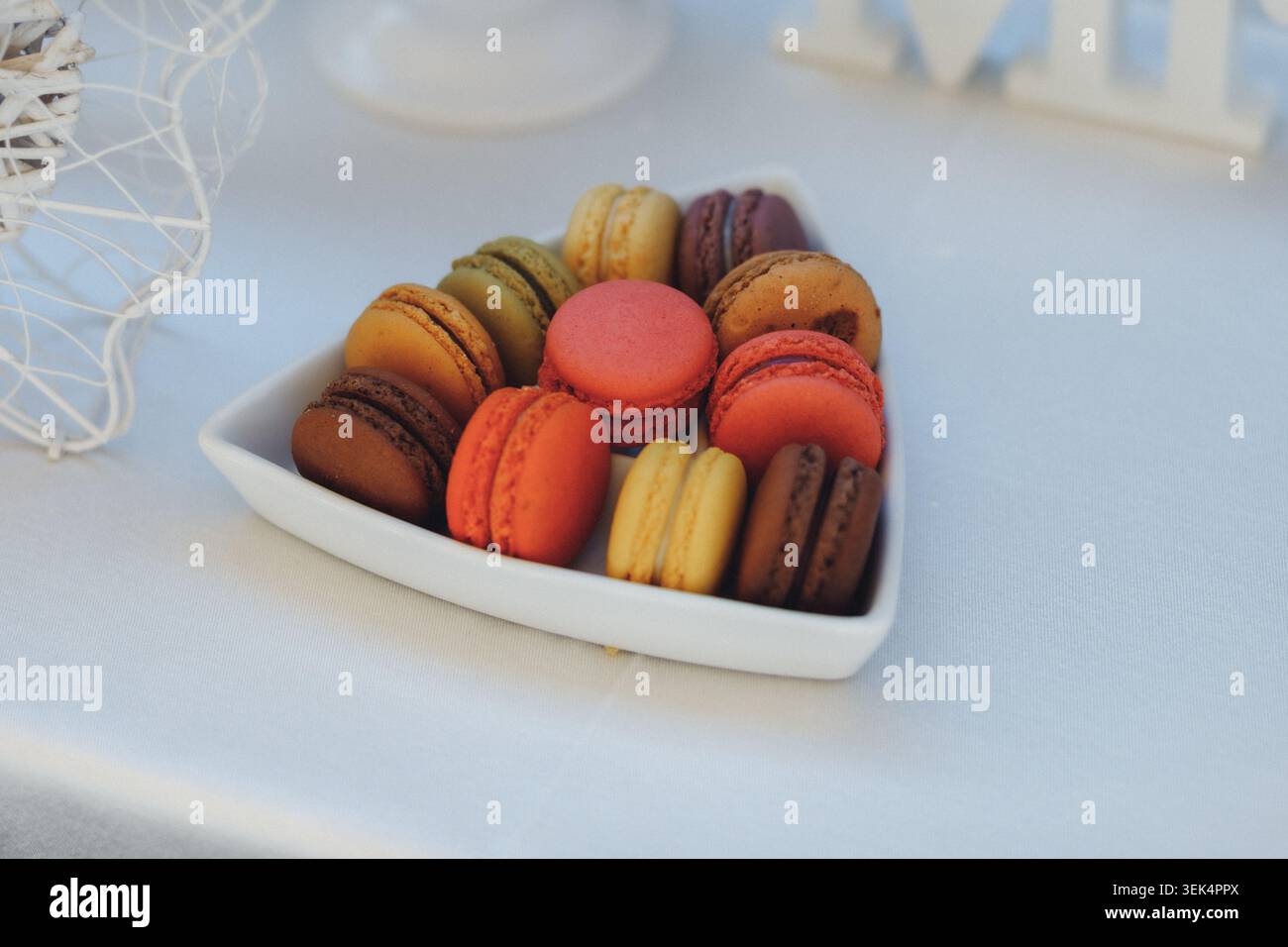 Macaron colorati in una ciotola bianca si siedono invitanti Foto Stock
