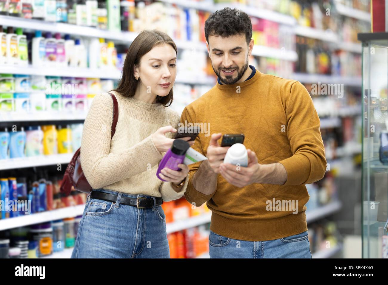Acquirenti di coppie sposate che eseguono la scansione del codice qr per shampoo o gel doccia in un negozio di prodotti chimici per uso domestico Foto Stock