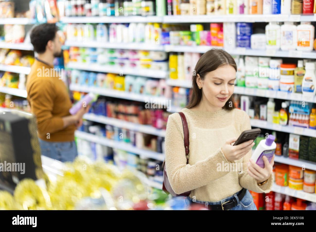 Acquirente donna che esegue la scansione del codice qr per shampoo o gel doccia in un negozio di prodotti chimici per uso domestico Foto Stock